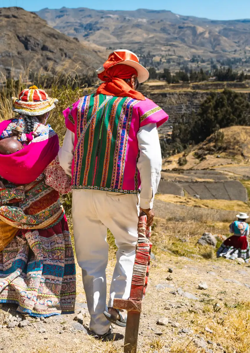 Casal em trajes andinos caminhando por um mirante sobre o vale