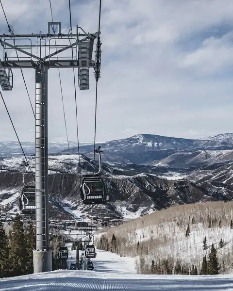 Teleférico sobre a pista de esqui, com as Montanhas Rochosas ao fundo, em Aspen