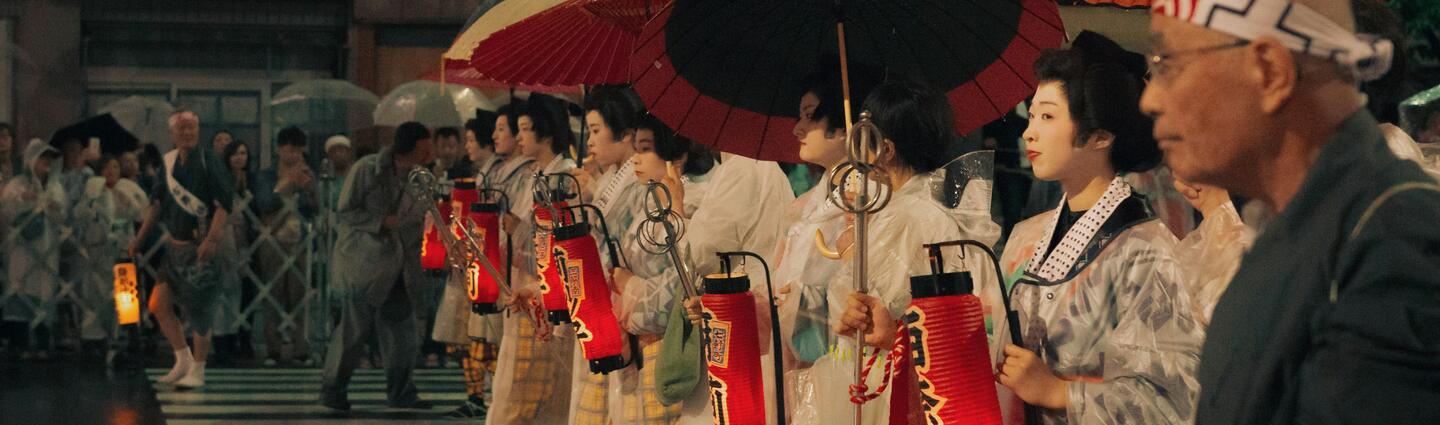 Procissão japonesa com lanternas e guarda-chuvas vermelhos.