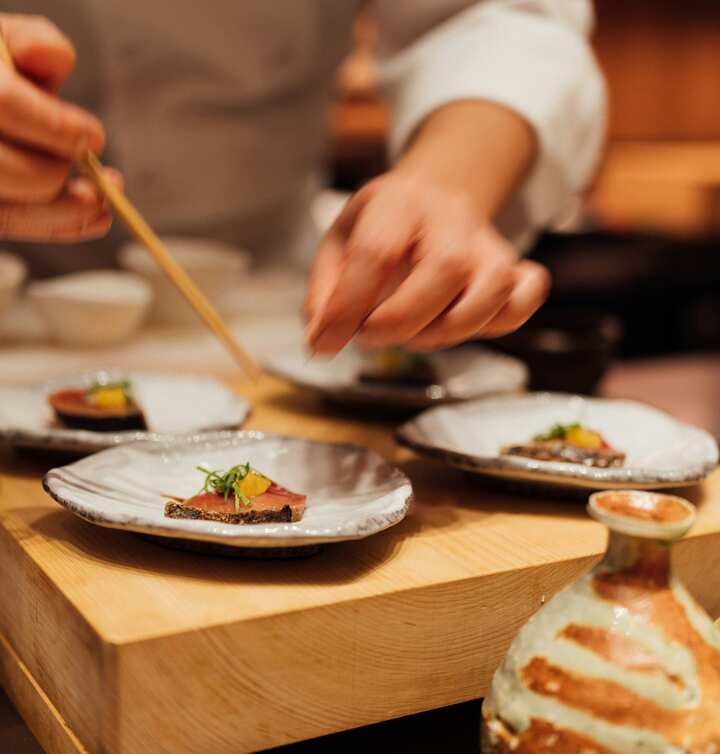 Chef finalizando pequenos pratos da gastronomia japonesa.