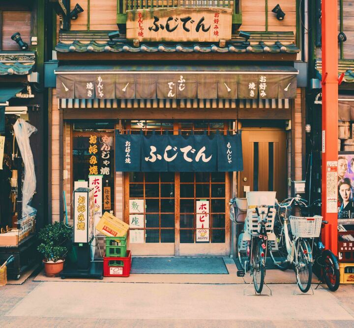Fachada de um pequeno restaurante japonês com lanternas acesas.